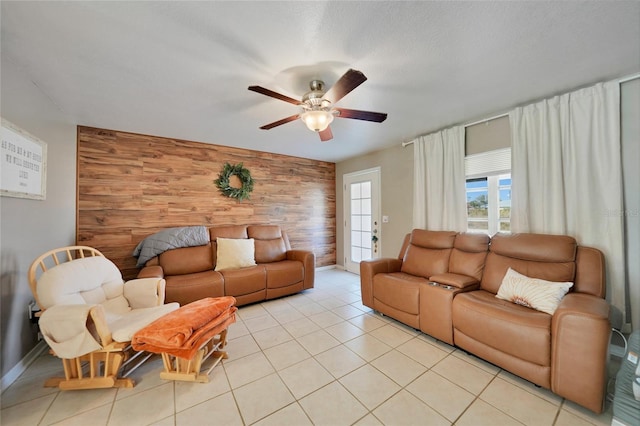 living room with wooden walls, ceiling fan, and light tile patterned flooring