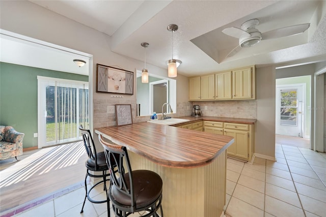 kitchen with decorative light fixtures, tasteful backsplash, a breakfast bar area, light tile patterned floors, and kitchen peninsula