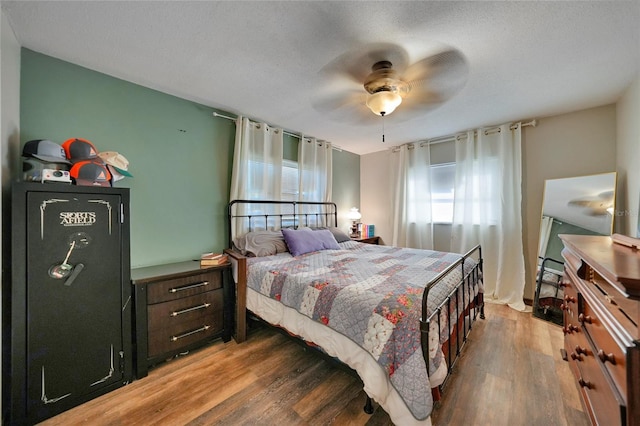 bedroom with dark wood-type flooring, a textured ceiling, and ceiling fan