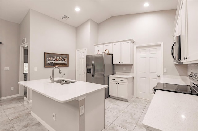 kitchen with a towering ceiling, stainless steel appliances, white cabinets, and a center island with sink