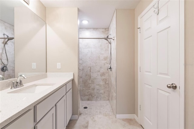 bathroom with a tile shower and vanity