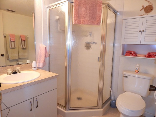 bathroom featuring a shower with door, vanity, tile patterned floors, and toilet