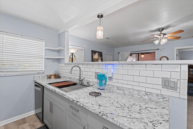 kitchen featuring decorative light fixtures, dishwasher, sink, backsplash, and a textured ceiling