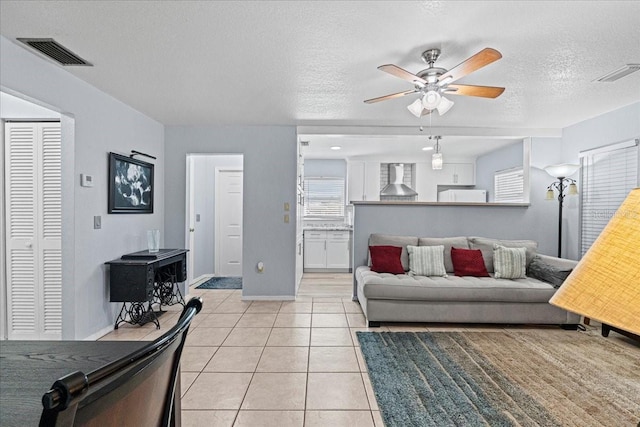 living room with ceiling fan, light tile patterned floors, and a textured ceiling