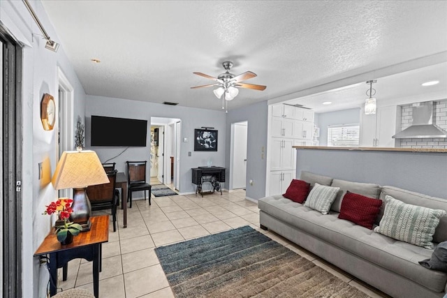 living room with ceiling fan, a textured ceiling, and light tile patterned flooring