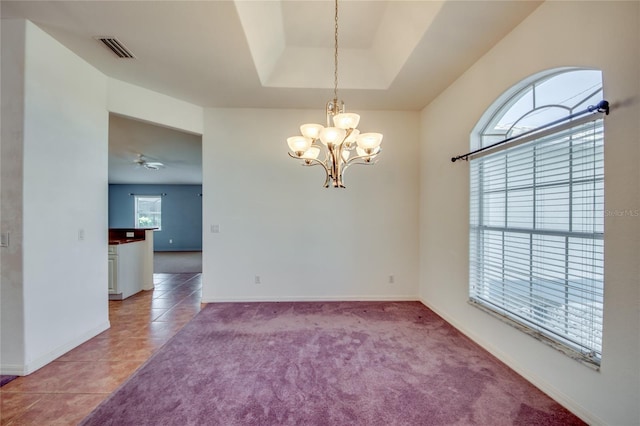 empty room featuring a tray ceiling, ceiling fan with notable chandelier, and light tile patterned flooring