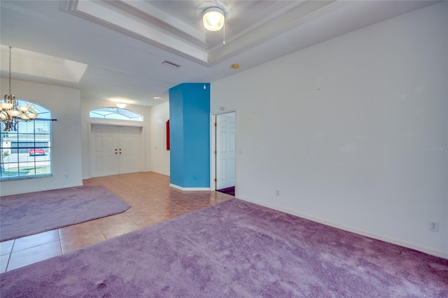 spare room with a raised ceiling, tile patterned floors, and a chandelier