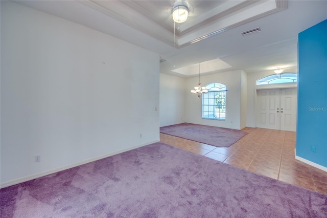 empty room featuring tile patterned floors, an inviting chandelier, and a tray ceiling