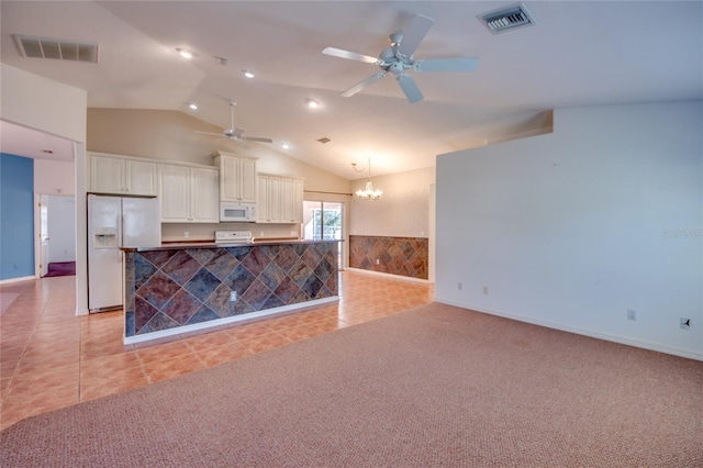 kitchen featuring vaulted ceiling, decorative light fixtures, white cabinets, light tile patterned floors, and white appliances