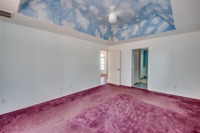 unfurnished bedroom featuring light colored carpet and a raised ceiling