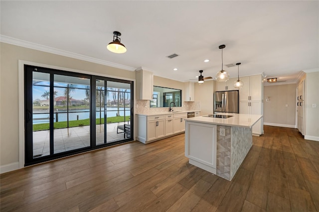 kitchen with pendant lighting, white cabinetry, sink, stainless steel refrigerator with ice dispenser, and a water view