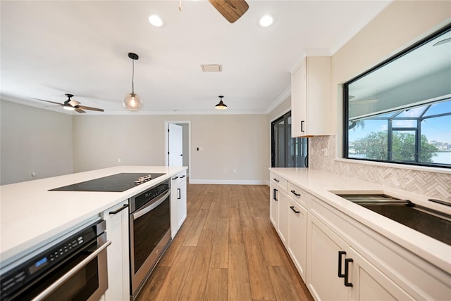 kitchen with black electric cooktop, oven, and white cabinets