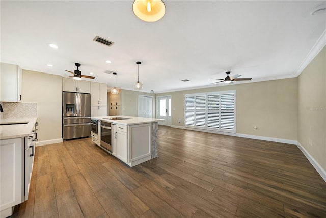 kitchen featuring hanging light fixtures, white cabinetry, a center island with sink, and stainless steel fridge