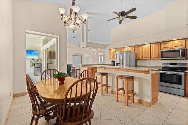 kitchen with light tile patterned floors, appliances with stainless steel finishes, hanging light fixtures, high vaulted ceiling, and a kitchen island