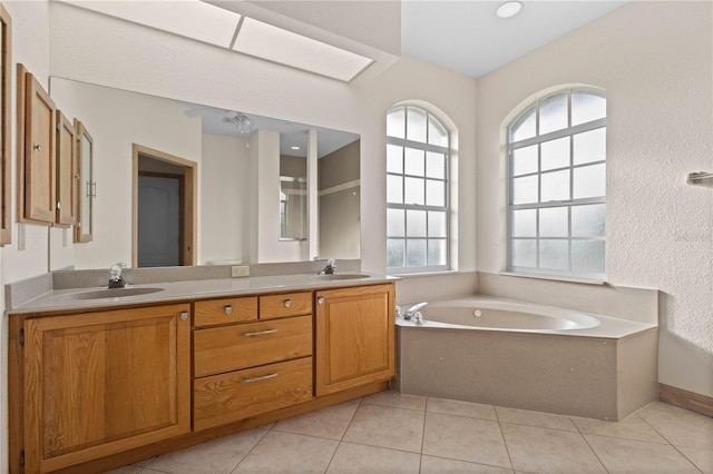 bathroom featuring tile patterned flooring, vanity, a bathing tub, and a skylight