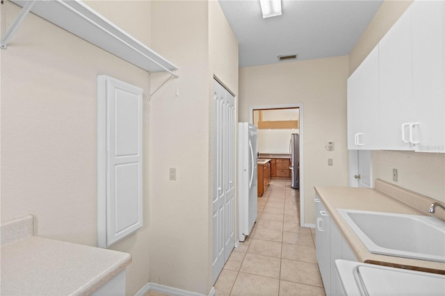 kitchen featuring sink, stainless steel fridge, white cabinetry, white refrigerator, and light tile patterned flooring