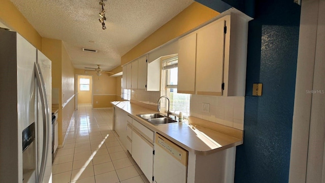 kitchen with light tile patterned flooring, sink, tasteful backsplash, dishwasher, and refrigerator with ice dispenser