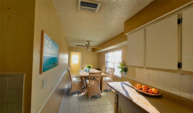 tiled dining room with ceiling fan and a textured ceiling