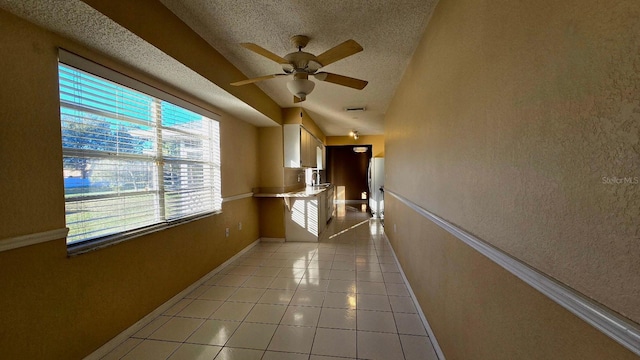 corridor featuring sink, a textured ceiling, and light tile patterned floors