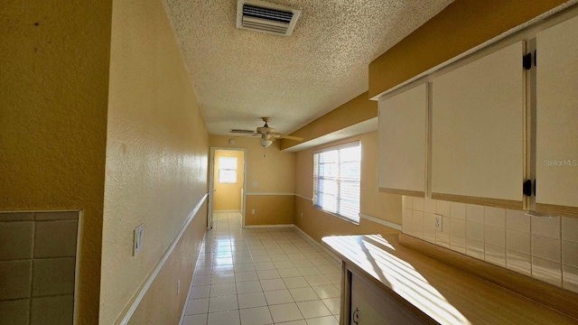 hall with a textured ceiling and light tile patterned flooring