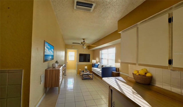 living room with light tile patterned flooring, ceiling fan, and a textured ceiling