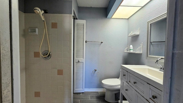 bathroom featuring vanity, toilet, and a tile shower