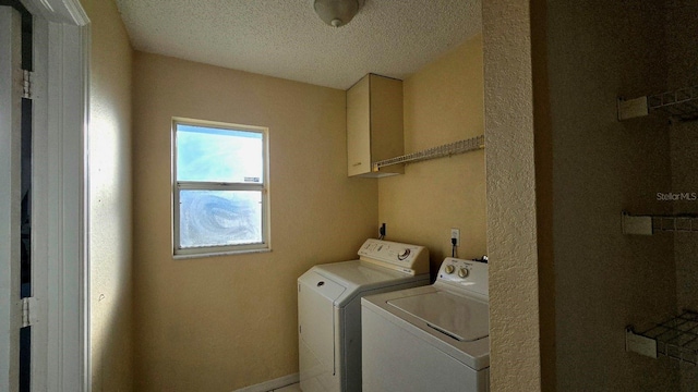 laundry area with cabinets, washer and dryer, and a textured ceiling