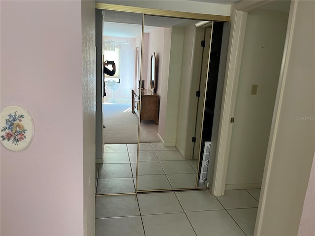 hallway with light carpet, baseboards, and light tile patterned floors