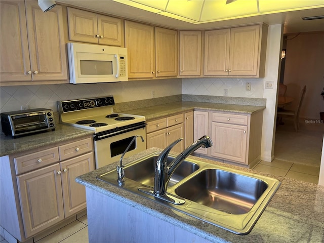 kitchen featuring light tile patterned flooring, light brown cabinets, a toaster, white appliances, and a sink