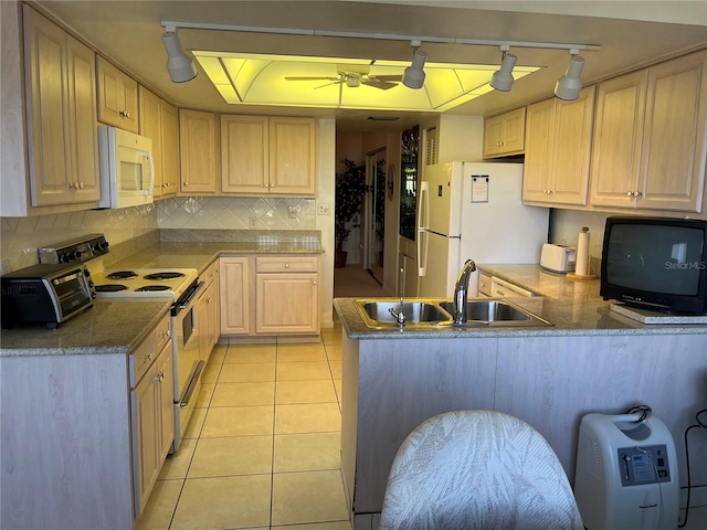 kitchen with white appliances, a toaster, a peninsula, light brown cabinets, and a sink