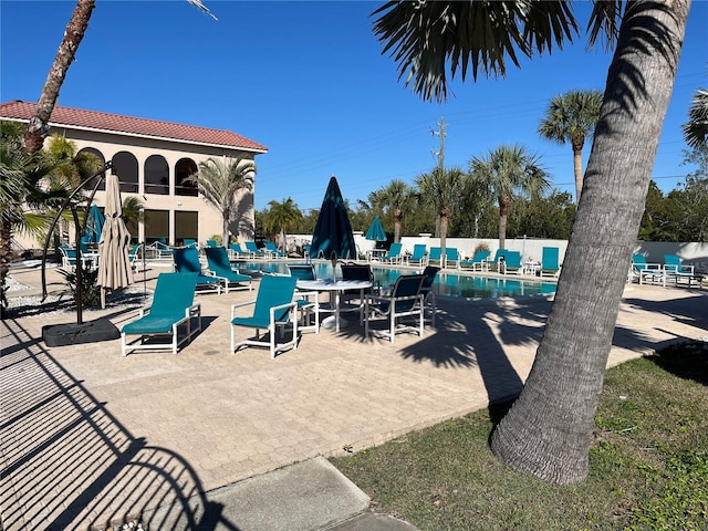 community pool with a patio area and fence