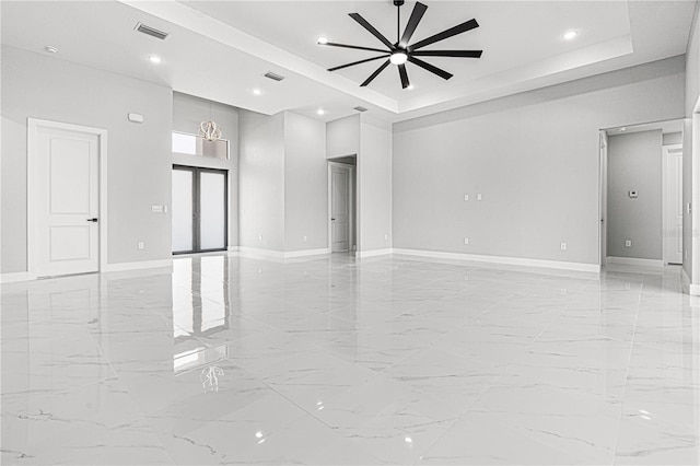 empty room with a tray ceiling, visible vents, and baseboards