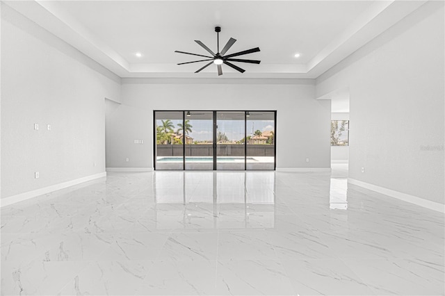 empty room featuring baseboards, a tray ceiling, a ceiling fan, and recessed lighting