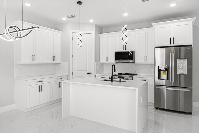 kitchen featuring a kitchen island with sink, white cabinets, light countertops, appliances with stainless steel finishes, and decorative light fixtures