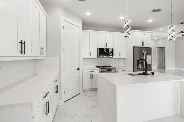 kitchen featuring a sink, white cabinets, appliances with stainless steel finishes, a center island with sink, and pendant lighting