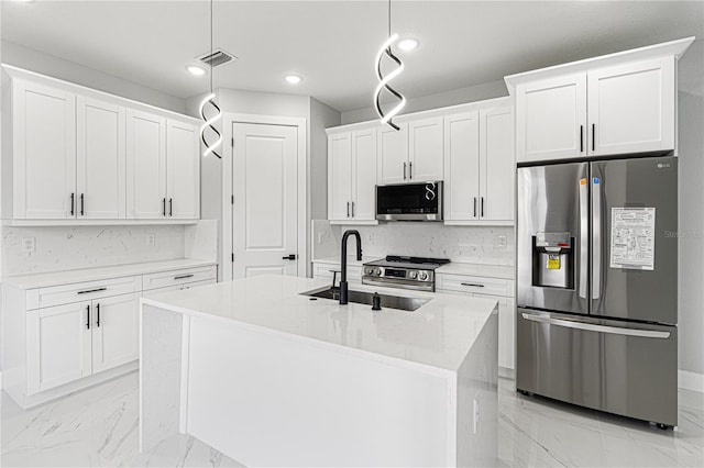 kitchen with a center island with sink, white cabinets, hanging light fixtures, marble finish floor, and stainless steel appliances