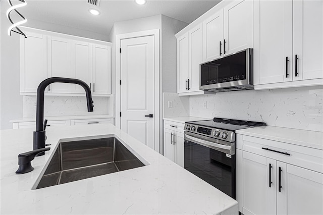 kitchen with tasteful backsplash, light stone counters, stainless steel appliances, white cabinetry, and a sink