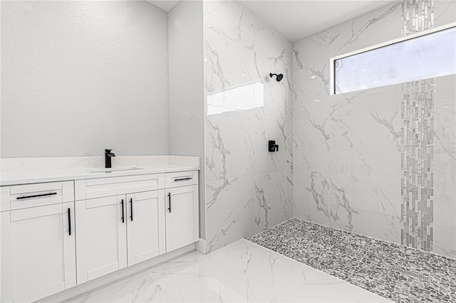 bathroom with a textured wall, marble finish floor, a marble finish shower, and vanity