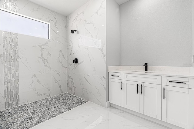 bathroom featuring a textured wall, marble finish floor, a marble finish shower, and vanity