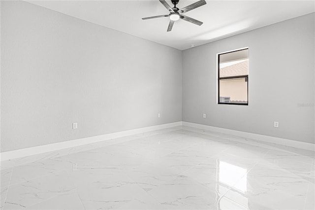 empty room featuring a ceiling fan, marble finish floor, and baseboards