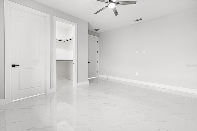 unfurnished bedroom with marble finish floor, a spacious closet, visible vents, and baseboards