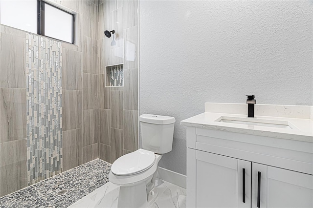 full bath with a textured wall, toilet, marble finish floor, vanity, and a walk in shower