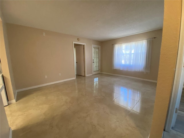 tiled empty room featuring a textured ceiling