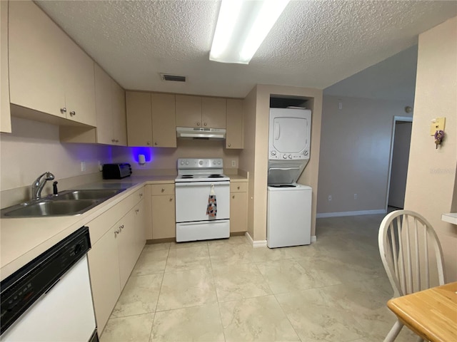 kitchen with sink, white appliances, stacked washer and clothes dryer, cream cabinets, and a textured ceiling