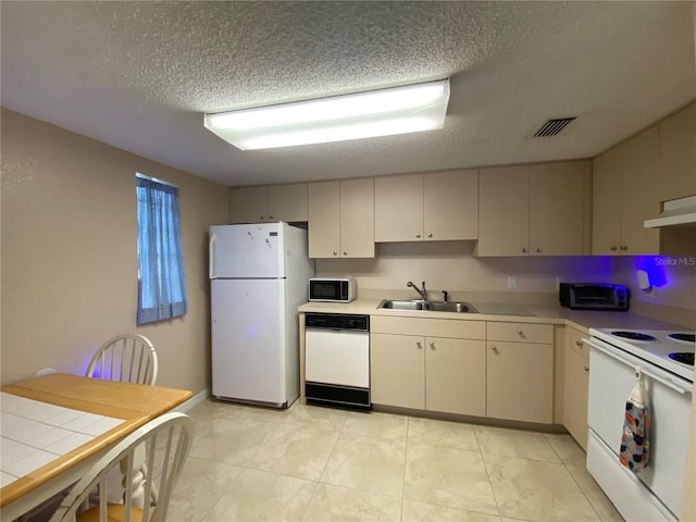 kitchen with sink, white appliances, cream cabinetry, and a textured ceiling