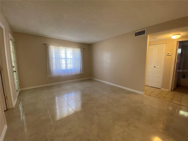 tiled empty room featuring a textured ceiling