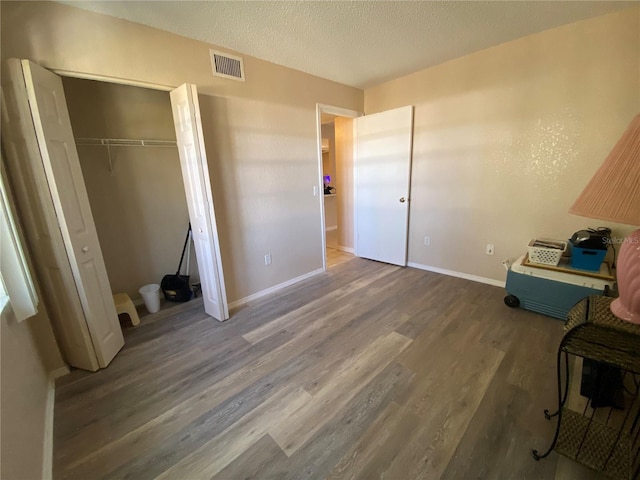 bedroom featuring dark wood-type flooring, a closet, and a textured ceiling