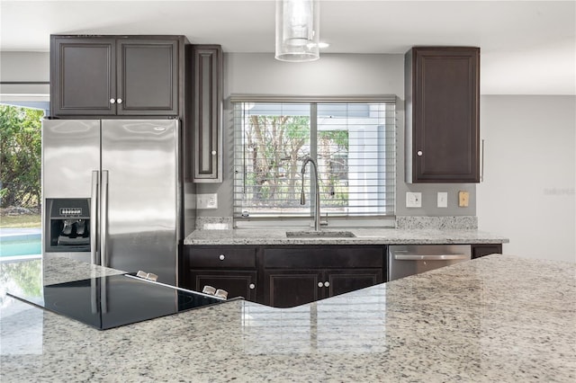 kitchen with hanging light fixtures, appliances with stainless steel finishes, a sink, and dark brown cabinetry