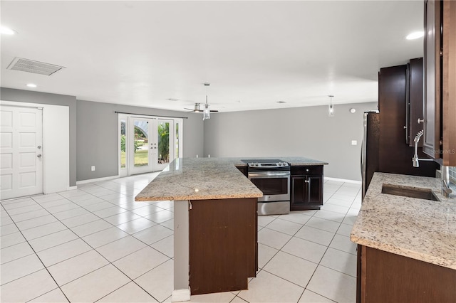 kitchen with light tile patterned floors, visible vents, a kitchen island, light stone countertops, and stainless steel appliances