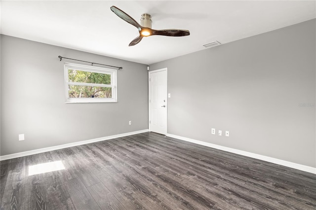 spare room featuring dark wood-style floors, visible vents, baseboards, and a ceiling fan